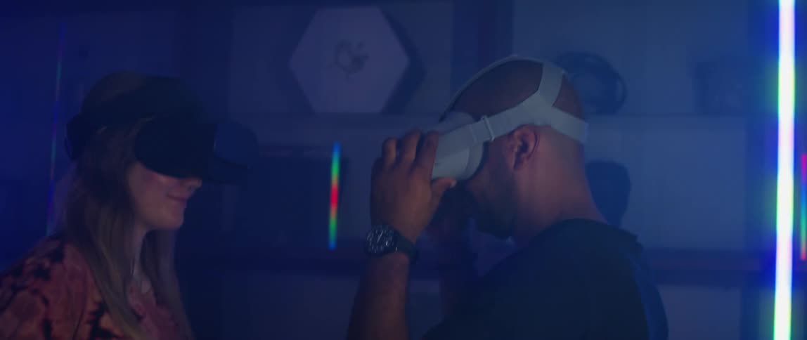 Man and woman putting on virtual reality headsets in futuristic room