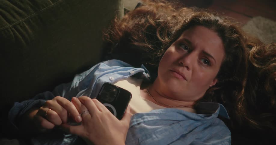 A sad woman fidgeting with her wedding ring while lying on a couch