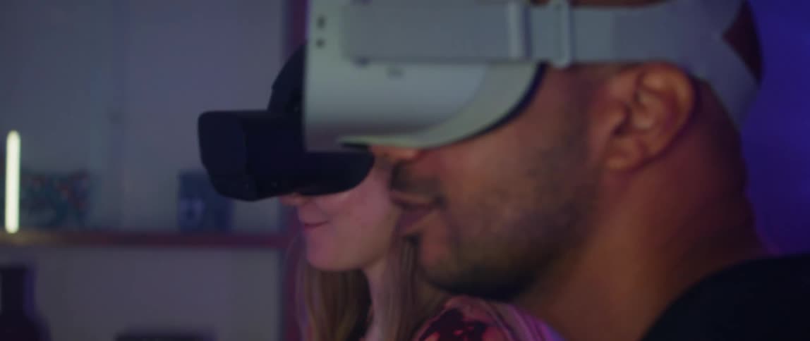 A man and woman smile and talk while wearing virtual reality headsets