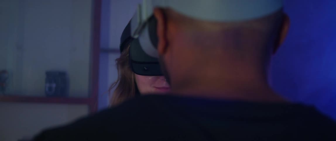 A man and woman are facing each other as they pull their virtual reality headsets over their eyes and turn away to play the game