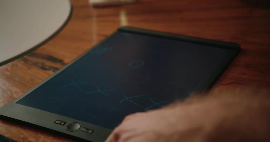 A man writing on a tablet on a wood table