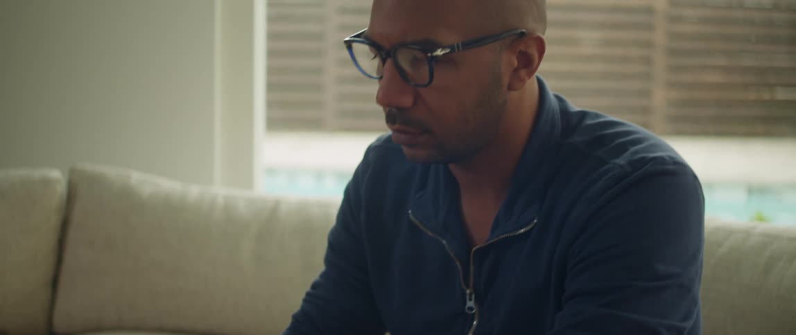 A man sits on a couch and types on a laptop