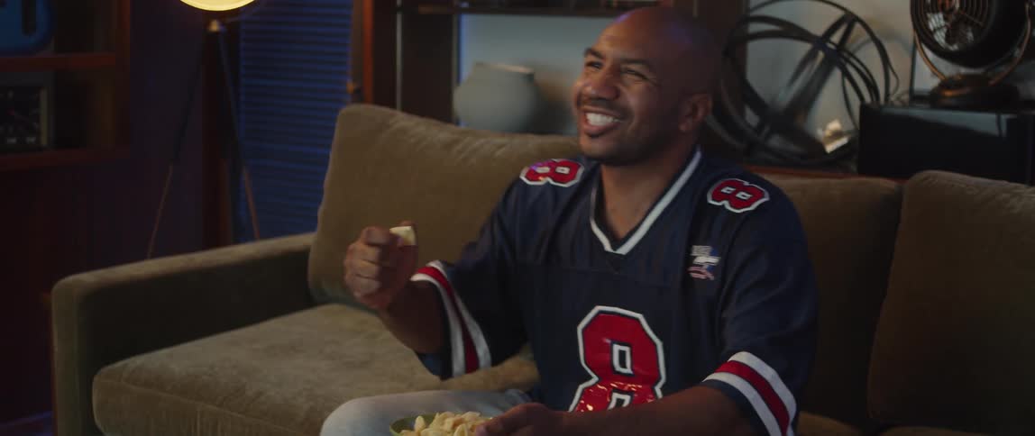 A man cheers and eats a snack