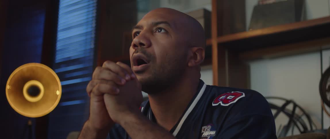 Bald man with jersey shirt watches sports match on television