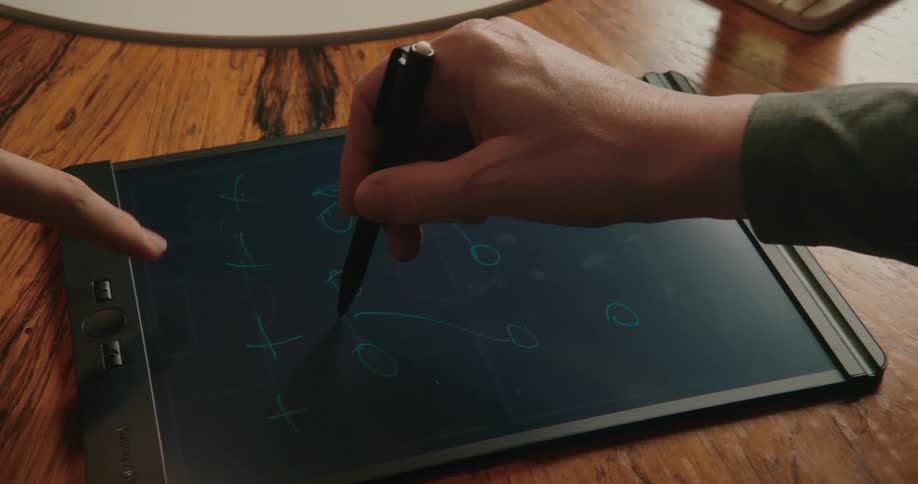 Group of friends plotting football strategy on a tablet over a wooden table