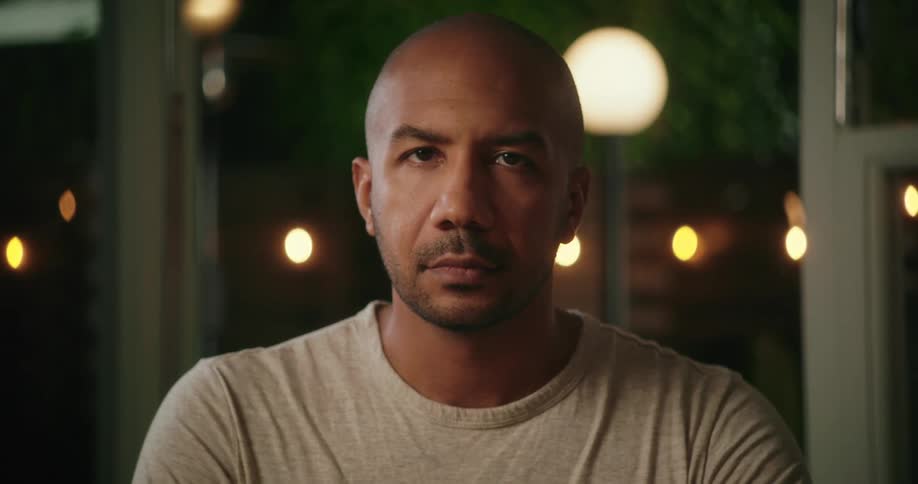 A man posing for the camera turns his head and looks at it expressionlessly