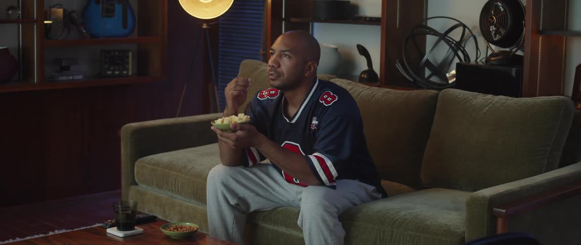 A man eats chips while watching sports on TV