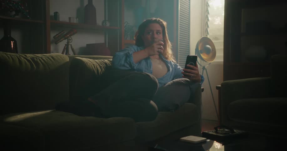 A woman is drinking on her couch