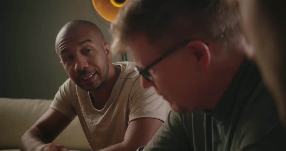 Three men chat while sitting on the couch