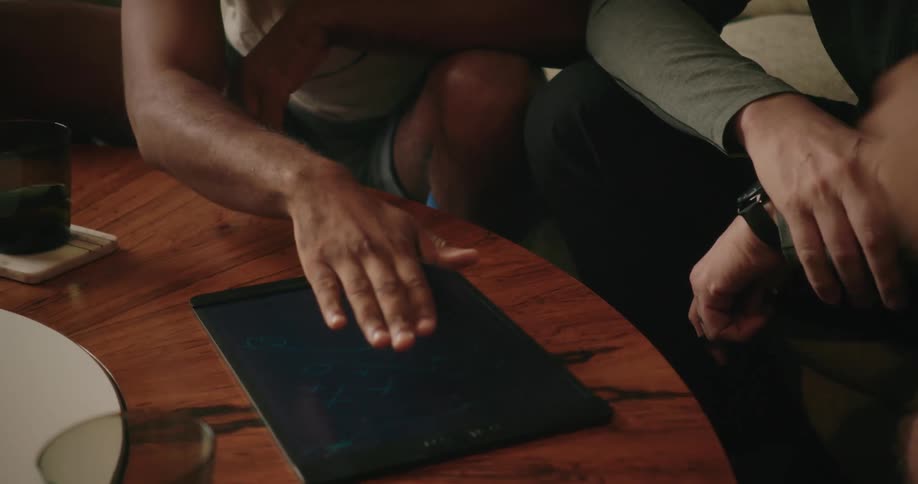 Group of friends plotting football strategy on a tablet over a wooden table