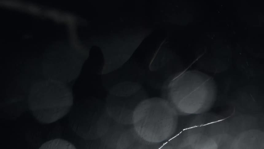 Abstract footage of a hand in front of lights as rain falls