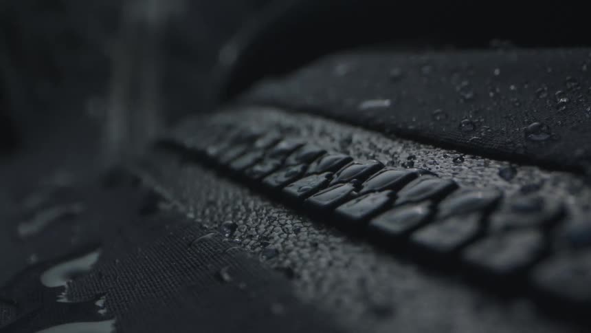 The camera tracks up the zipper on a black rain jacket