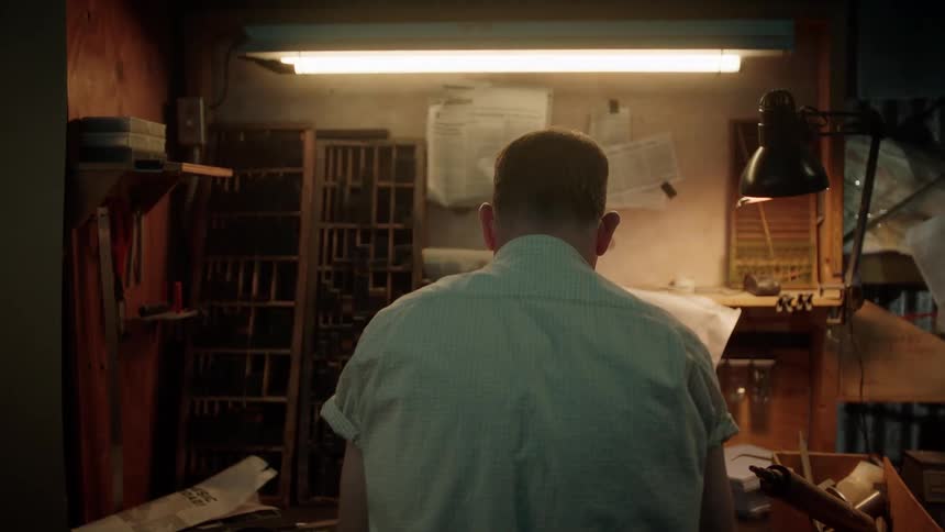 Back of the head of a man working on a small workshop startled when lights flicker
