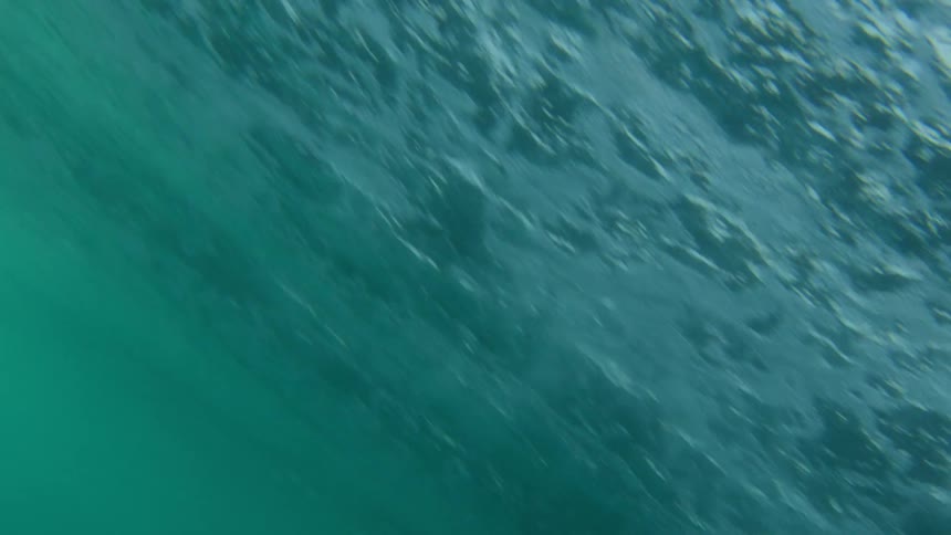 Underwater footage of air bubbles forming under an ocean wave rolling overhead