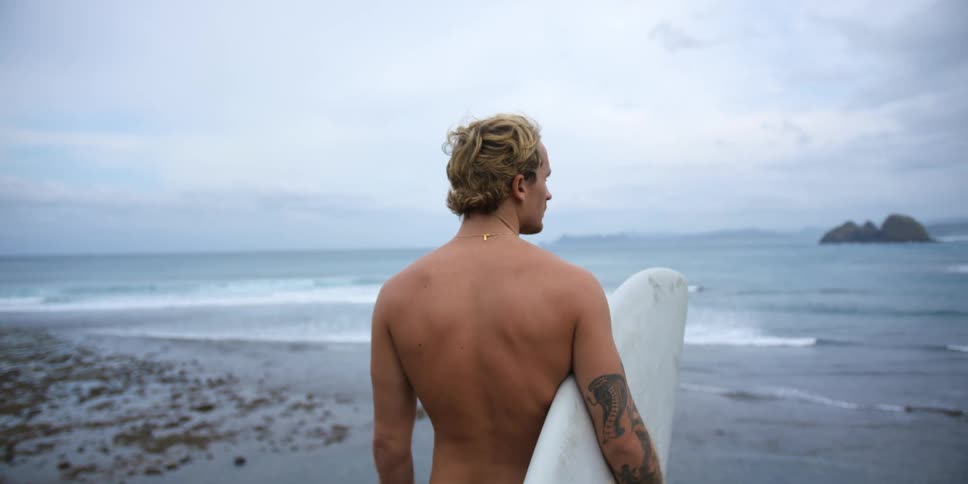 A man is standing on the beach with a surfboard