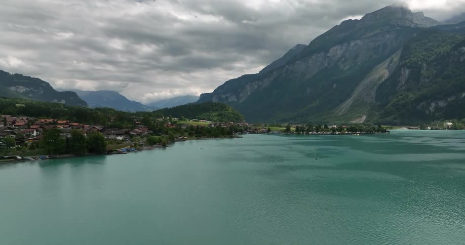 Aerial view of coastal town and high and steep mountains under clouds