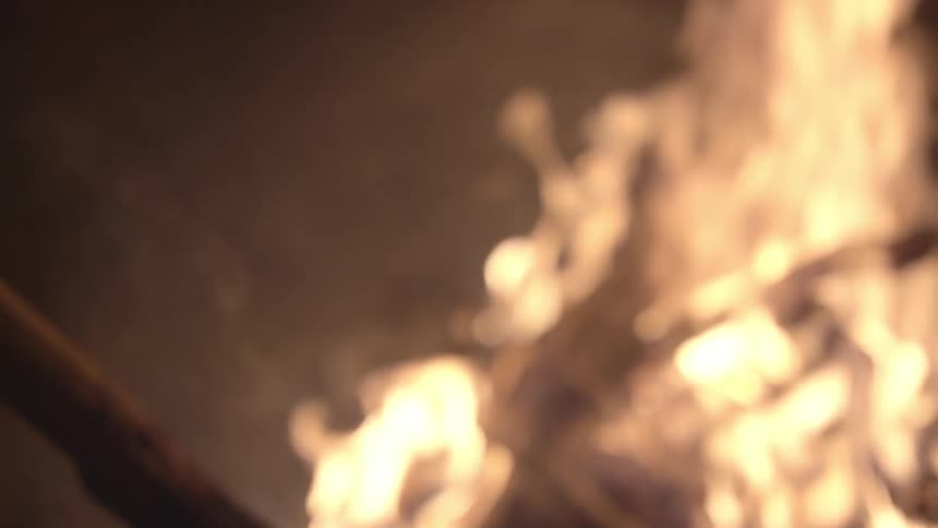 A person is stirring a fire with a stick