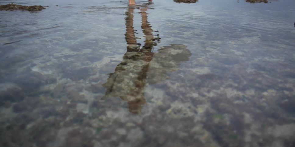 A man walks down rocks along the coast