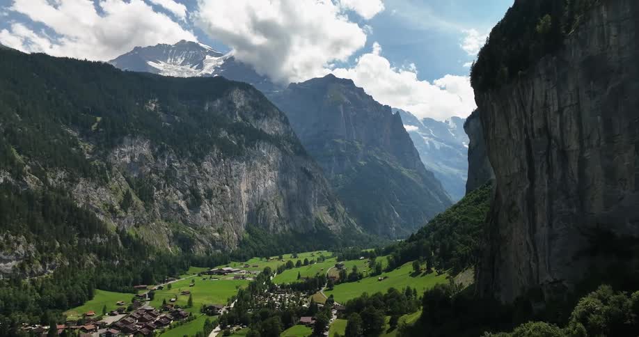 Aerial view of town in green valley and high and steep mountains