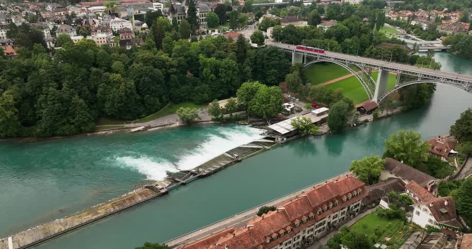 A train moves on a bridge over a river in a town