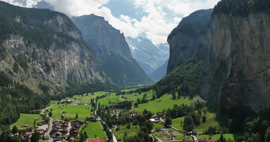 Aerial view of town in green valley and high and steep mountains