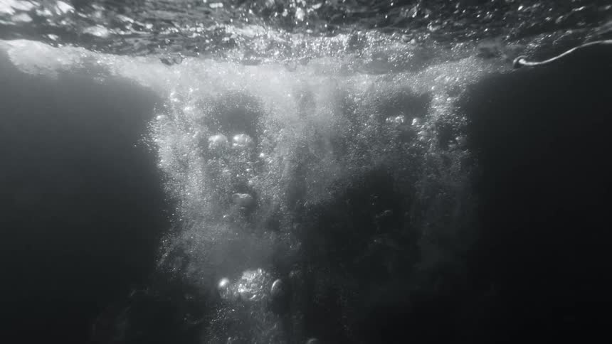 A person dives deep into dark water