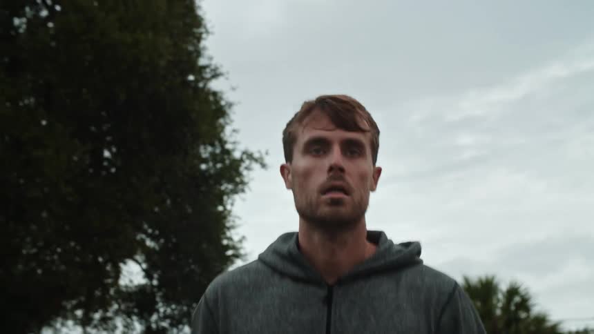A man is jogging under a cloudy sky