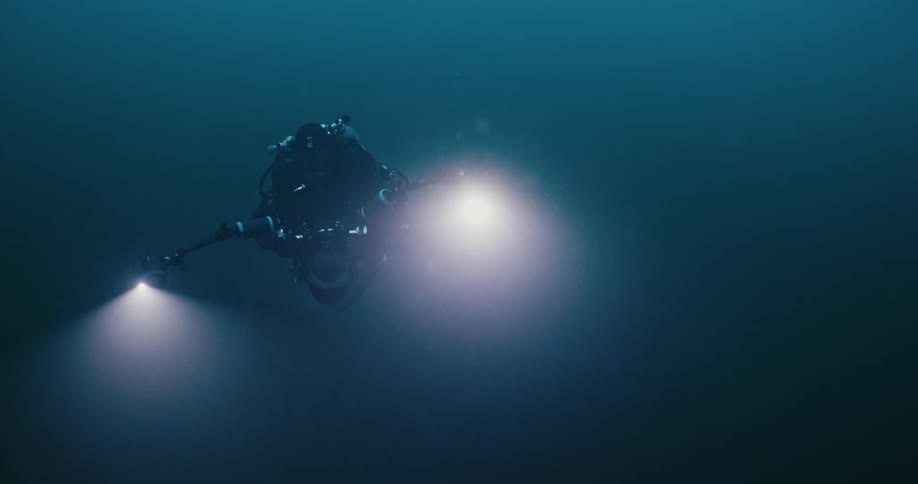 A diver wears headlamps while underwater