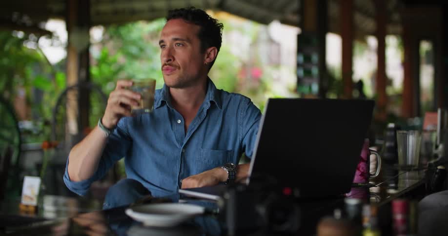 A man drinks coffee while using his laptop