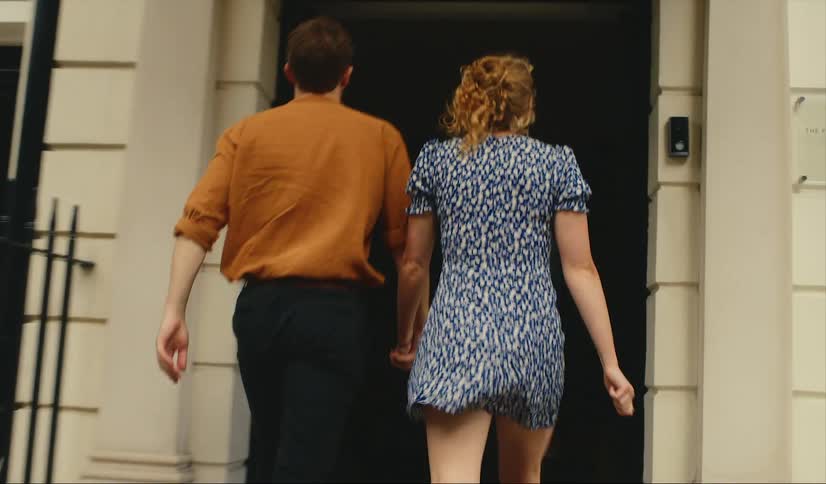 A man and woman walk into a hotel building holding hands