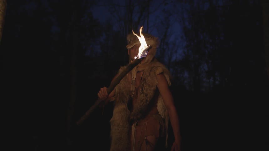 A native american man uses torch to see at night