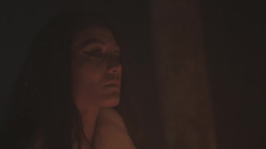 A woman dances in front of firelight