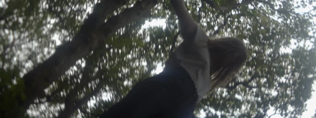 A young woman spins around in the woods with her arms outstretched