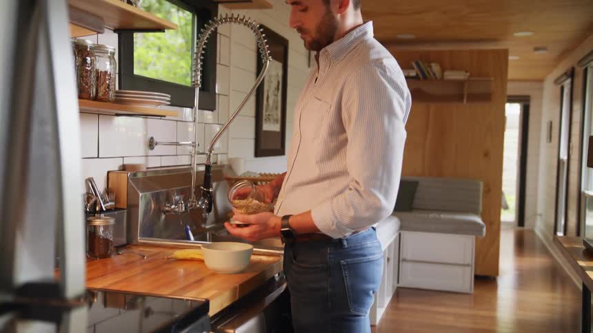 Man serves a bowl of cereal on the kitchen of a small modern house
