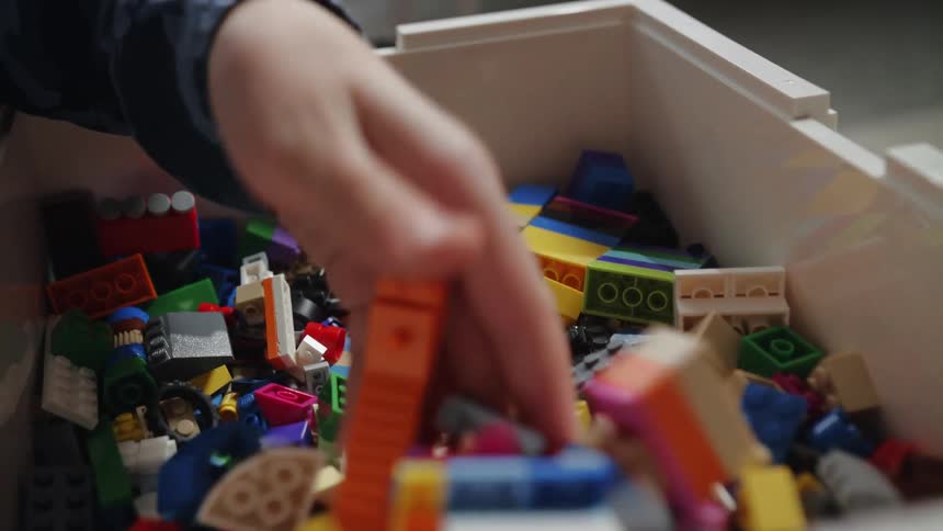 A child digging through a plastic bin of legos