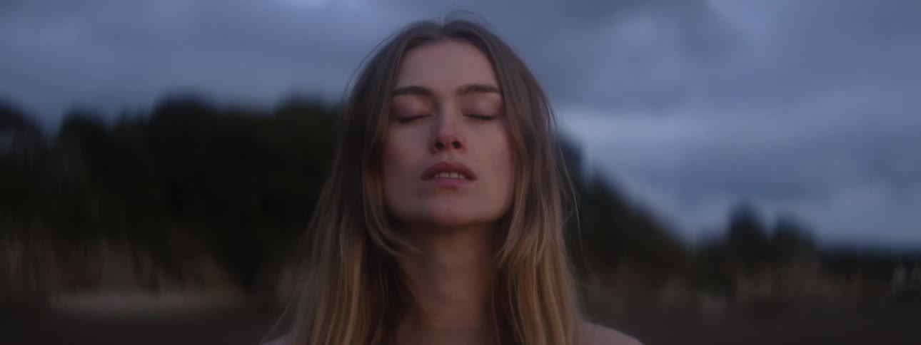 A woman standing outside with her eyes closed