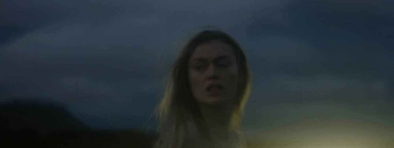 A woman walking outside at night turns around and nervously looks behind her