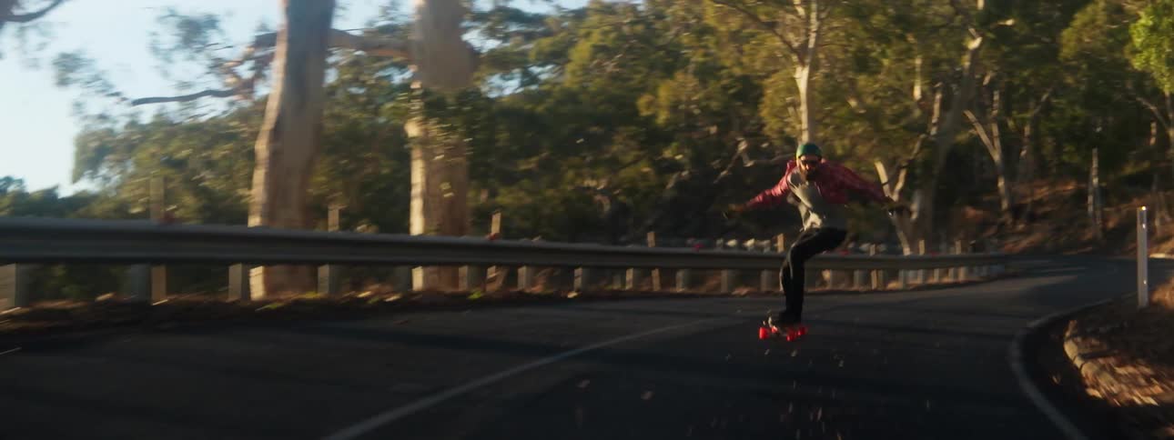 A man rides his skateboard down the middle of a highway