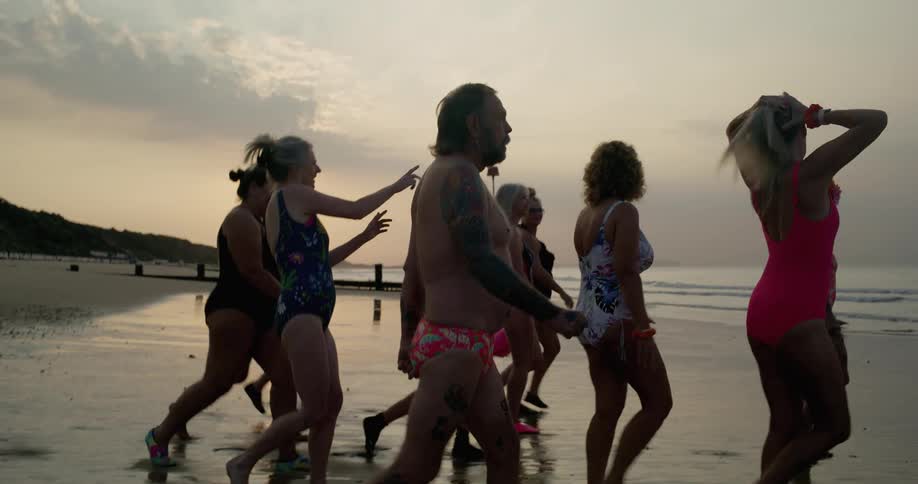 A group of men and women walk on the beach