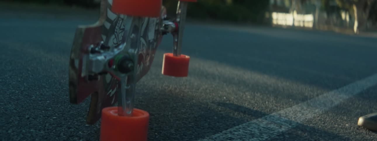 A person drops a skateboard in a parking lot