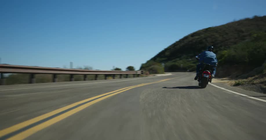 A motorcyclist makes several sharp turns while driving along a winding road