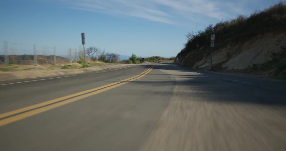 The camera races forward along a curved road that passes through a remote area
