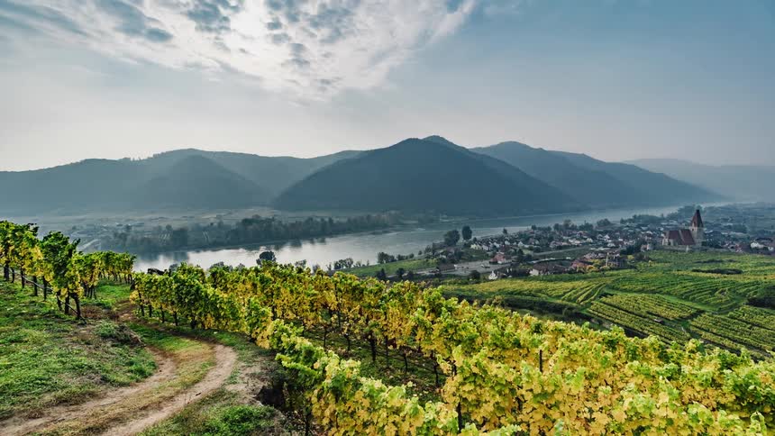 A time lapse of a rural community is shown with cloud movement sped up and mountains and a small community in the background