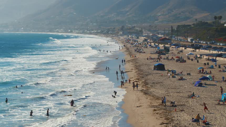 Aerial view of people lying down on the beach and swimming in the sea
