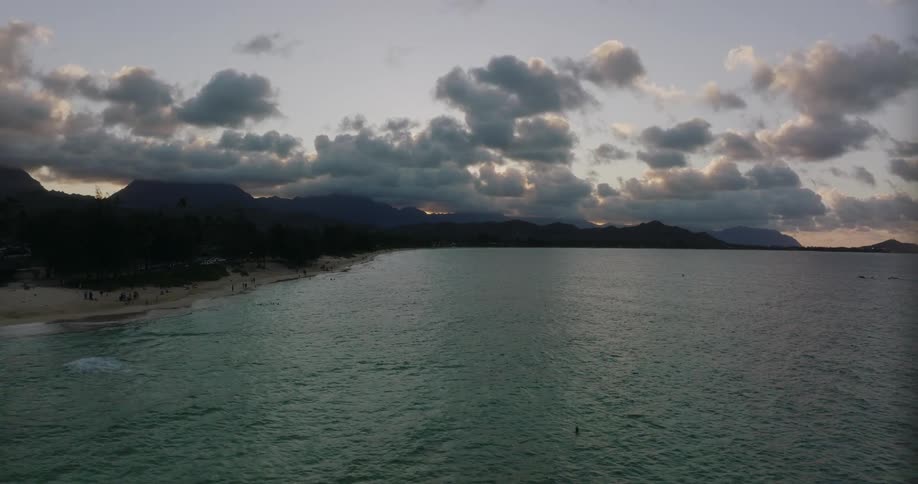 Aerial view of a small coastal town next to the ocean while the sun sets behind the mountains