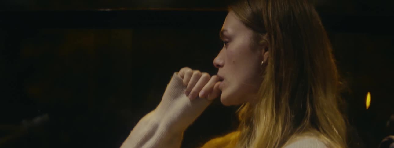 A woman outside atnight nervously biting her finger