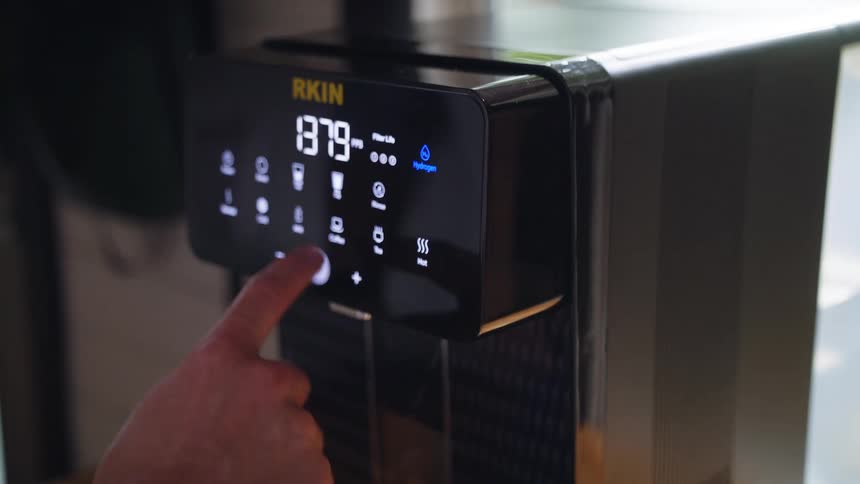 A person pressing buttons on a coffee maker at home