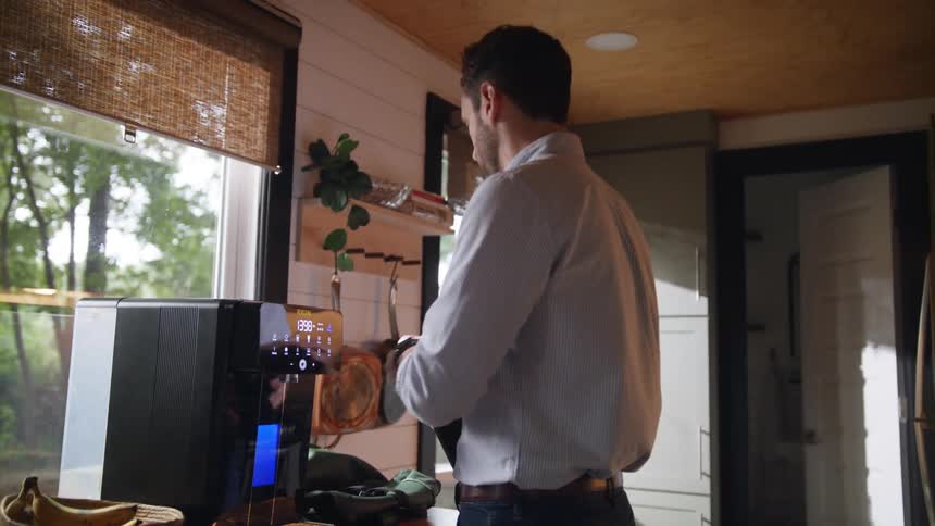 A man preparing a drink at a coffee maker at home