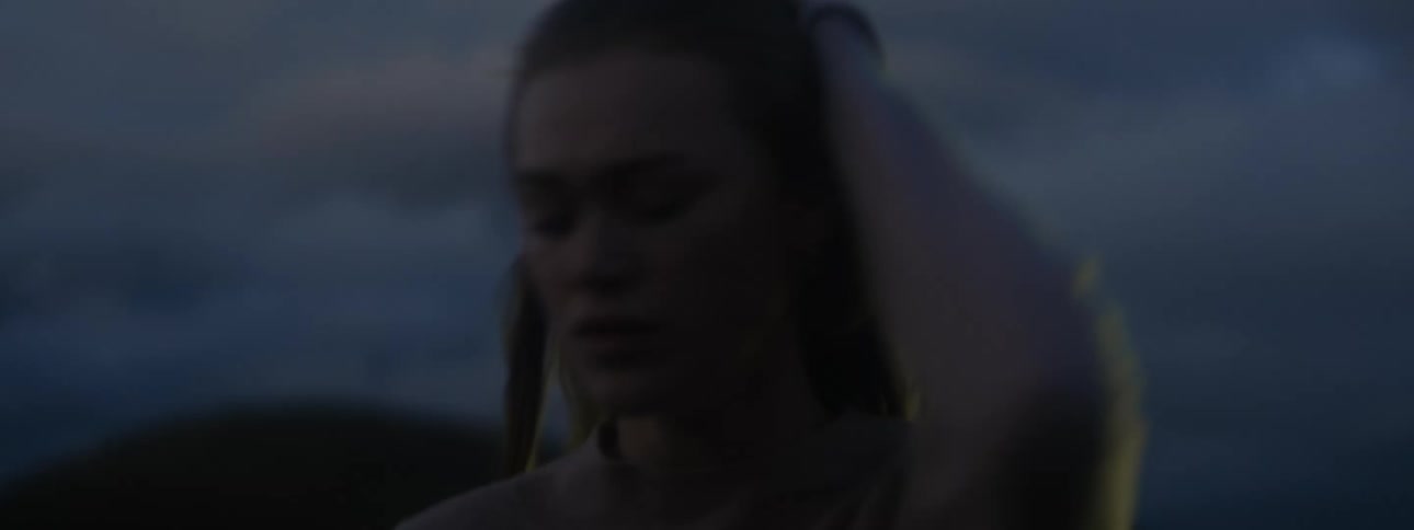 Woman walks around frowning as bright light shines in the background
