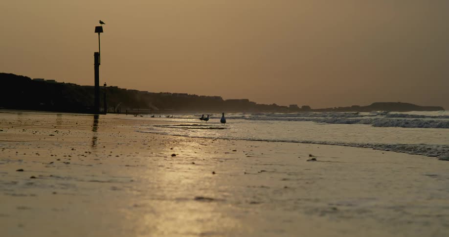 Ocean waves break against the beach at sunset